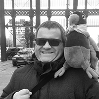 http://On%20voit%20un%20homme%20sourire%20avec%20des%20lunettes%20de%20soleil%20et%20un%20perroquet%20en%20peluche%20sur%20l'épaule%20gauche