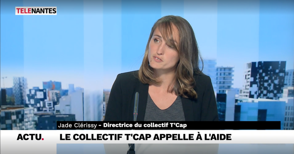 photo d'une femme blanche aux cheveux chatain mi-long sur un plateau de télévision avec écrit "appelle à l'aide du collectif t'cap"