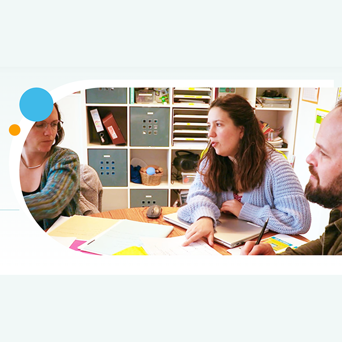 photo de 3 personnes autour d'une table où il y a des documents