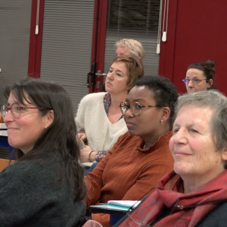 photo de plusieurs personnes assises dans une salle, elles regardent quelque chose hors-champ