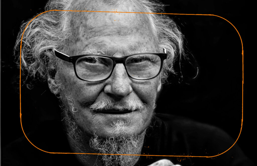photo en noir et blanc d'un homme blanc avec des lunettes, des cheveux et une barbe blanche